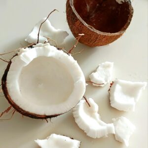 Home Close-up of a freshly cracked coconut with white flesh pieces spread on a clean surface.