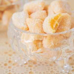 Home Crystal bowl filled with sweet sugar-coated passion fruit candies on a lacy table.