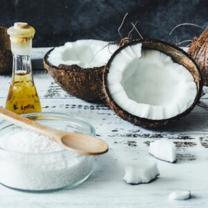 Home Arrangement of coconut oil, flakes, and whole coconuts on a rustic wooden table.