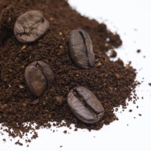 Home Detailed close-up of roasted coffee beans and ground coffee on a white background.