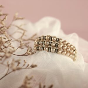 Close-up of a pearl bracelet with delicate details on a soft pink fabric.