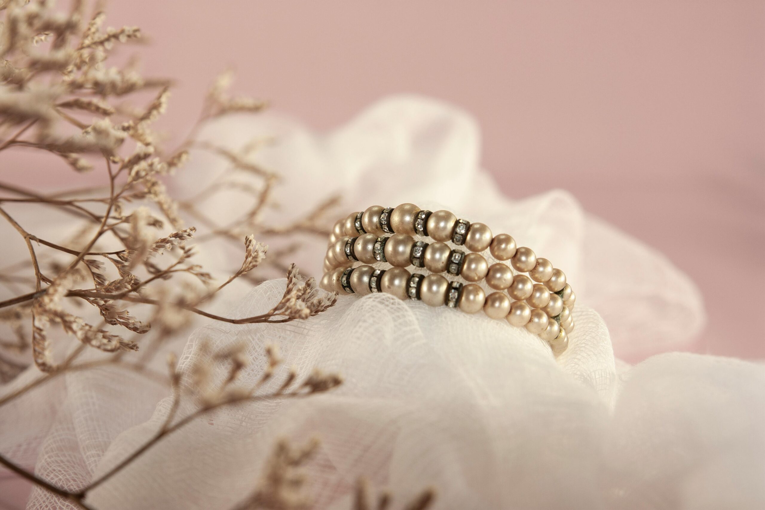 pexels photo 8281588 8281588 Close-up of a pearl bracelet with delicate details on a soft pink fabric.